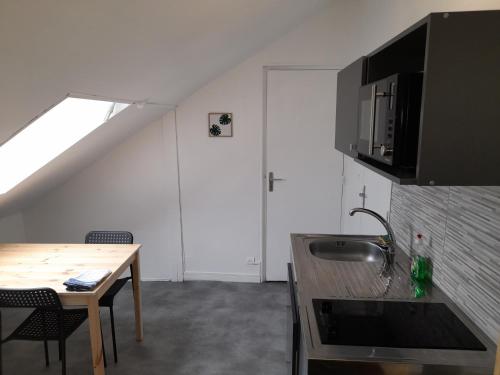 - une cuisine avec un évier et une table dans une chambre dans l'établissement LOGEMENT VERT proche de NEOMA et de la CATHEDRALE de REIMS, à Reims