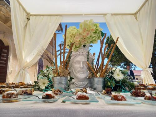 a table with plates of food and a vase of flowers at Casolare del Toscano Country Rooms in Caltagirone