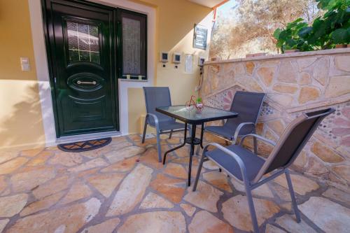a patio with a table and chairs and a green door at Cleopatra rooms in Nikiana
