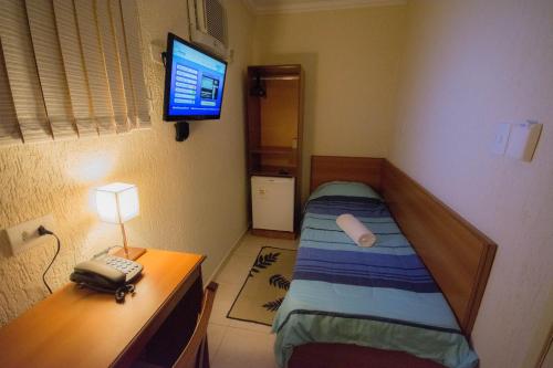 a small room with a bed and a desk and a television at Hotel Estação Paraíso - ao lado do Metrô Paraíso e 600m da Av Paulista in Sao Paulo