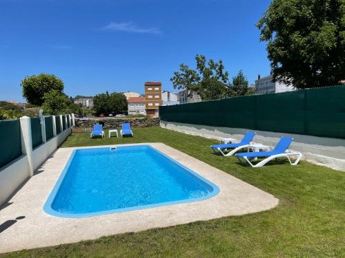 a swimming pool with two lawn chairs and two chairs at Pension San Anton in Melide