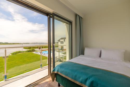 シフィノウイシチェにあるApartamenty Blisko Naturyのベッドと大きな窓のある寝室