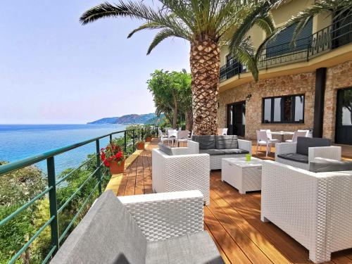 a balcony with white chairs and a view of the ocean at Villa Anita Apartments in Capo dʼOrlando