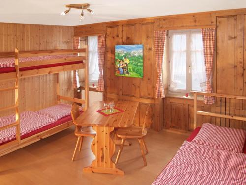 Boardercamp Laax - swiss mountain hostel في Ruschein: غرفة مع طاولة وسريرين بطابقين