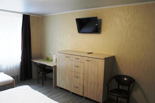 een hotelkamer met een bureau en een televisie aan de muur bij Вилла ALEX in Vinnytsya