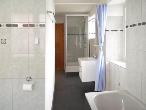 ein Badezimmer mit einer Badewanne, einem WC und einem Waschbecken in der Unterkunft Boardercamp Laax - swiss mountain hostel in Ruschein