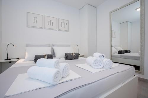 a white bed with towels on it with a mirror at Sunny Apartments Rab in Rab