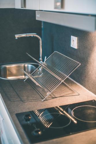 - un évier de cuisine avec un portant en métal sur la cuisinière dans l'établissement La Pomponnette du Bassin, à Arcachon