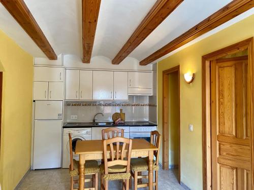 a kitchen with white cabinets and a table and chairs at Casa Campolé in San Juan de Plan