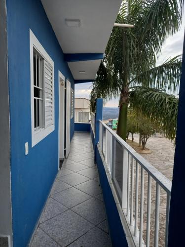 Cette maison bleue dispose d'un balcon avec un palmier. dans l'établissement Pousada avenida 03, à São Thomé das Letras