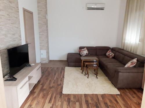 un salon avec un canapé brun et une télévision dans l'établissement Adriatic Sunset House, à Petrovac na Moru