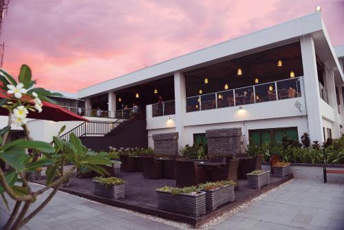 un edificio con un restaurante con personas sentadas en el balcón en Timor Plaza Hotel & Apartments en Dili