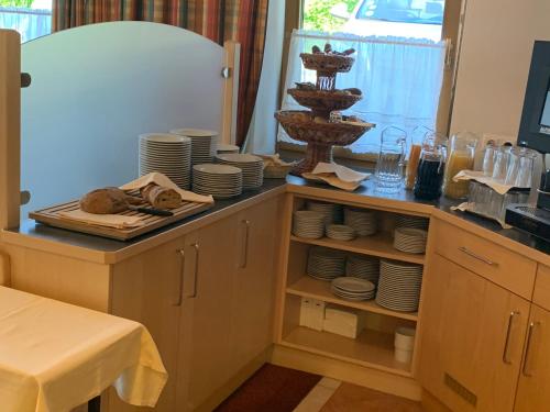 eine Küche mit einer Theke mit Tellern und Geschirr in der Unterkunft Hotel Schneeberger in Niederau