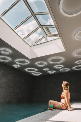 a woman in a bikini sitting in a swimming pool with a window at Hôtel 1770 & Spa in Le Pontet