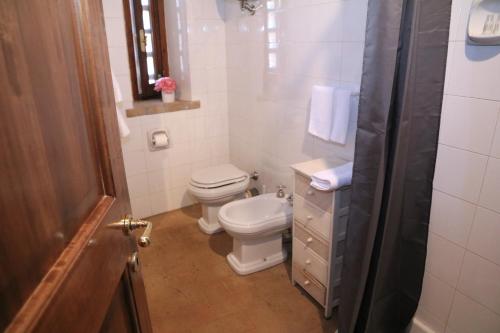 a white bathroom with a toilet and a sink at Corte Fratini Appartamenti in Trevi