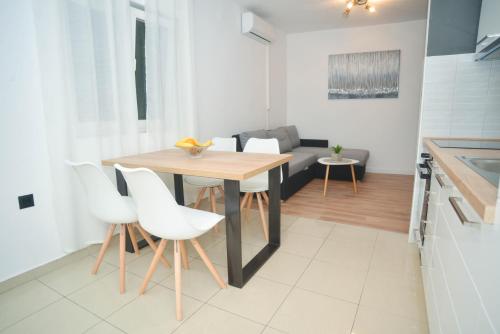 a kitchen with a wooden table and white chairs at Apartment Ante in Biograd na Moru