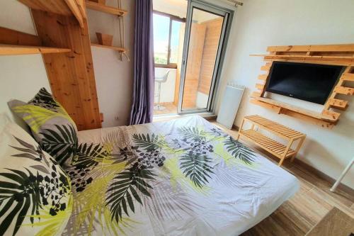 a bedroom with a bed and a flat screen tv at Très charmant studio Plage du Penon in Seignosse