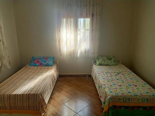 two beds in a small room with a window at Jardin de rayane in Essaouira