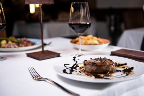 a table with a plate of food and a glass of wine at Hotel Osteria della Pista dal 1875 in Casorate Sempione