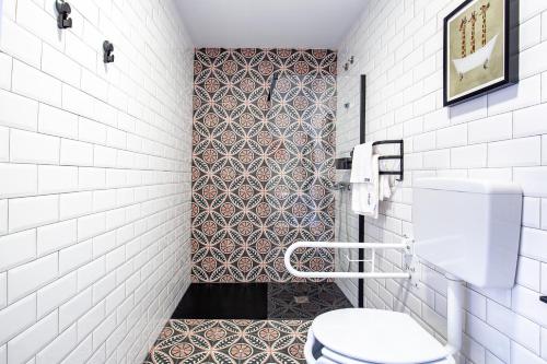 a bathroom with a toilet and a tile wall at Apartamentos Rurales Cielo de Monfragüe in Malpartida de Plasencia