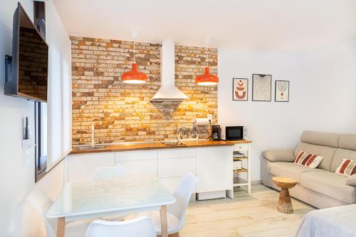 a kitchen and living room with a brick wall at Apartamentos Rurales Cielo de Monfragüe in Malpartida de Plasencia