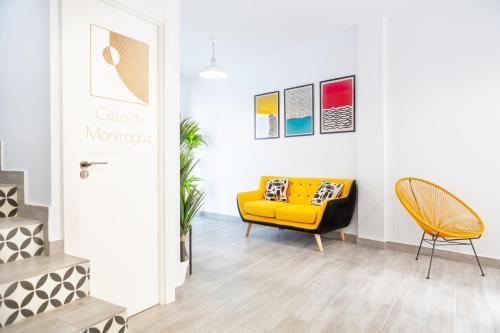 a yellow couch and a chair in a room at Apartamentos Rurales Cielo de Monfragüe in Malpartida de Plasencia