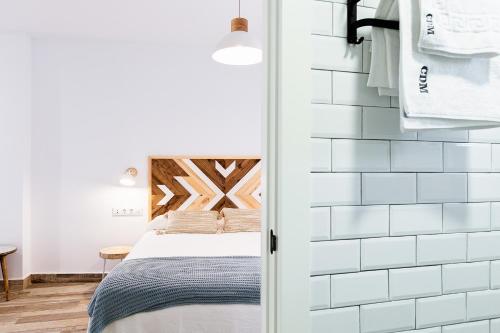 a bedroom with a bed and a white tiled wall at Apartamentos Rurales Cielo de Monfragüe in Malpartida de Plasencia