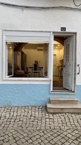 a white and blue building with a window and a door at Coração da Vila in Alcochete