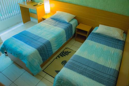 a bedroom with two beds and a table with a lamp at Hotel Estação Paraíso - ao lado do Metrô Paraíso e 600m da Av Paulista in Sao Paulo