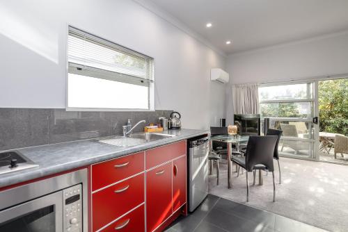 a kitchen with red cabinets and a table with chairs at TWO FOUR COLOGNE in Martinborough 