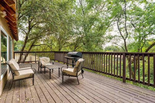 a wooden deck with chairs and a grill on it at Mountain Trail Lodge and Vacation Rentals in Oakhurst