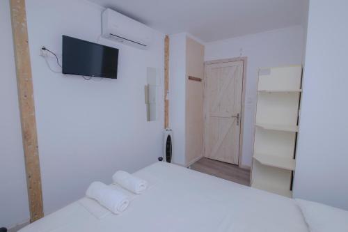 a white bedroom with a bed and a tv on the wall at Orfeas Studios in Vasiliki