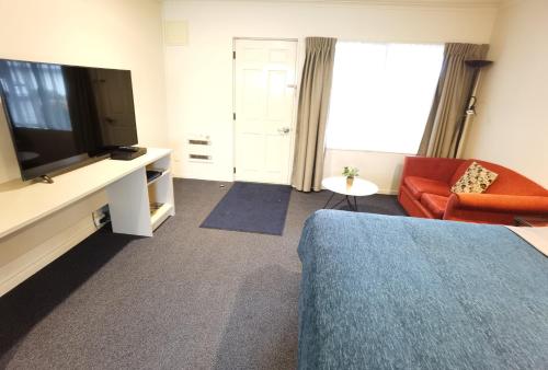 a living room with a television and a couch at Harringtons Motor Lodge in Palmerston North