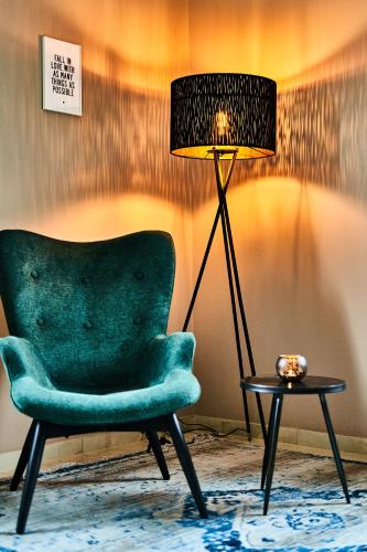 a green chair sitting next to a lamp and a table at PRIMERA Villa in Singen