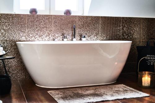 a white tub in a bathroom with a tile wall at PRIMERA Villa in Singen