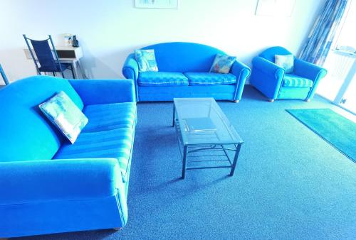 a living room with blue couches and a coffee table at Harringtons Motor Lodge in Palmerston North