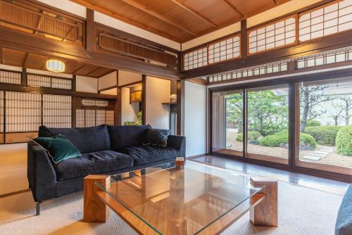 sala de estar con sofá negro y mesa de cristal en Heritage Osaka, en Tondabayashi
