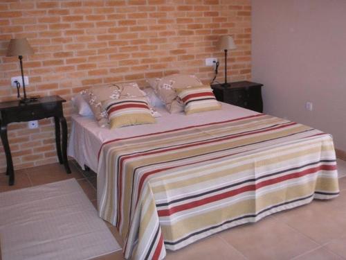 1 cama grande con almohadas y pared de ladrillo en Villas La Fuentita en Gran Tarajal