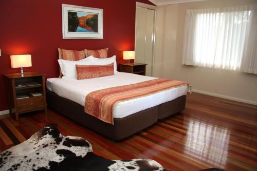 - une chambre avec un grand lit aux murs rouges dans l'établissement Yabbaloumba Retreat, à Booloumba