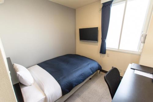 a bedroom with a bed and a desk and a window at Frame Hotel Sapporo in Sapporo