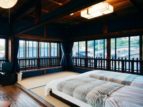 LAMP Iki في إكي: غرفة نوم بسرير كبير في غرفة بها نوافذ