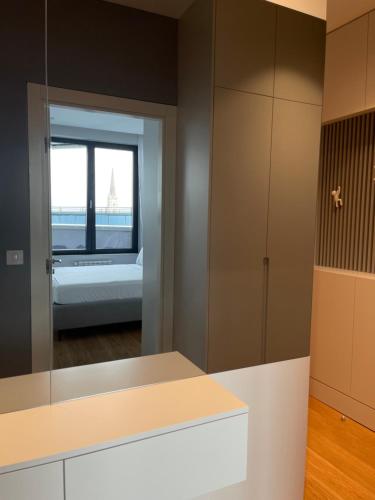 uma cozinha com um espelho e uma cama num quarto em Pupin Palace Apartments em Novi Sad
