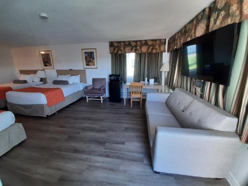 a hotel room with two beds and a couch at Howard Johnson by Wyndham Woodstock NB in Woodstock