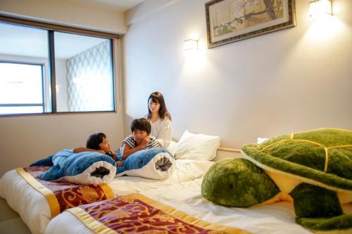 kobieta i dwoje dzieci leżących na łóżku w obiekcie Hotel Chula Vista SENAGA -SEVEN Hotels and Resorts- w mieście Naha