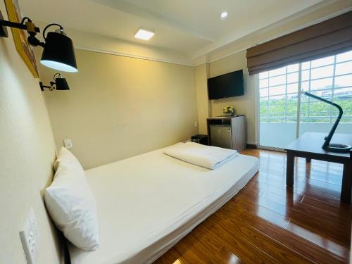 a large white bed in a room with a desk at Good For You Hotel in Ho Chi Minh City