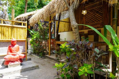 een rood standbeeld dat voor een gebouw staat bij Puri Hondje in Gili Trawangan