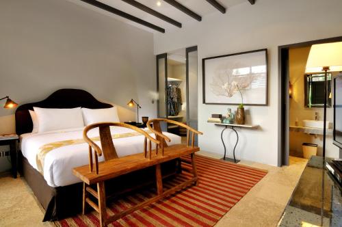 a bedroom with a bed and a bench and a bathroom at Room & Vespa 1 in Seminyak