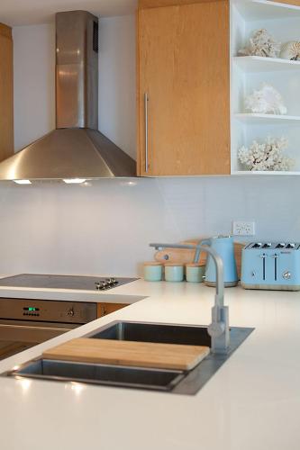 a kitchen counter with a sink and a stove at Papillon Coolum in Coolum Beach