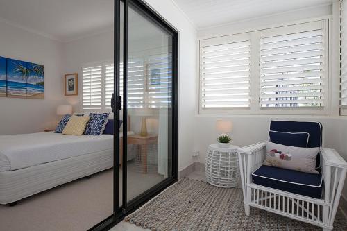 a bedroom with a bed and a chair and windows at Papillon Coolum in Coolum Beach