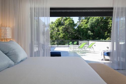 a bedroom with a bed and a balcony with chairs at Papillon Coolum in Coolum Beach
